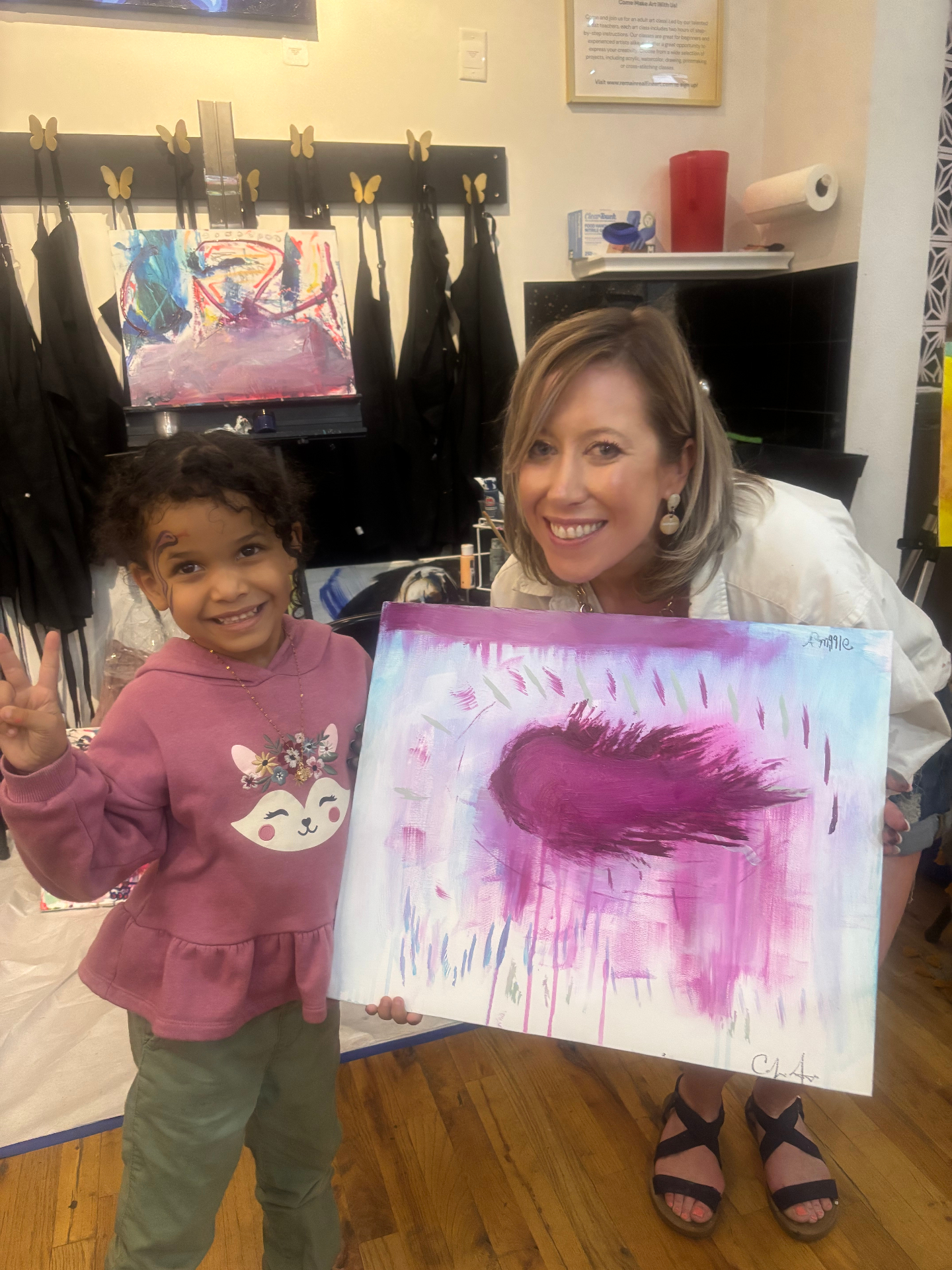 Amillie proudly holding up her finished pink and blue painting